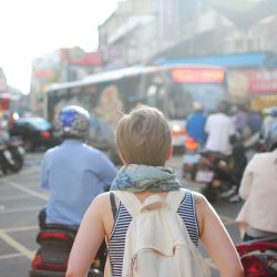 woman wearing backpack walking on road
